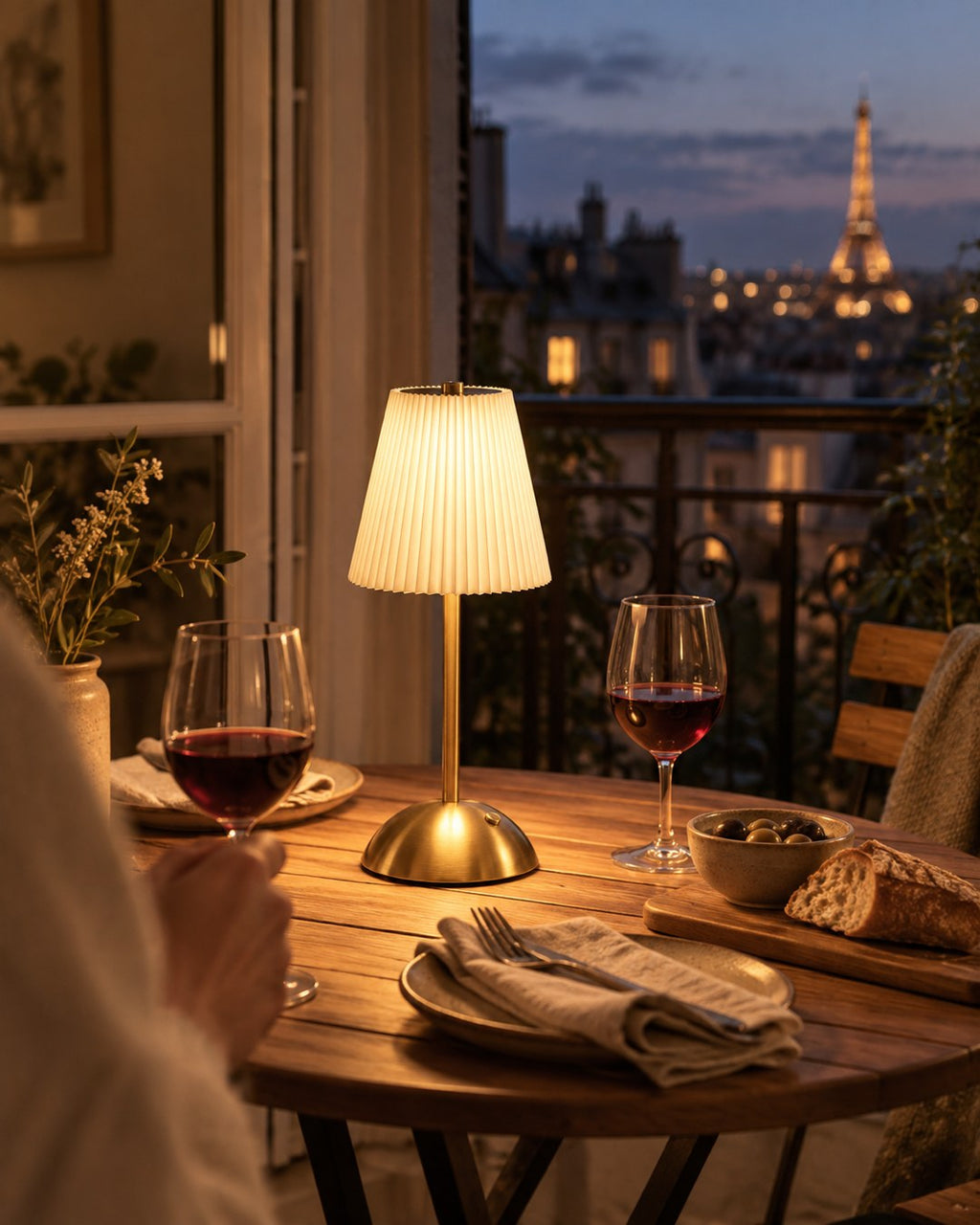 Lampe sans fil plissée allumée sur une table de dîner près d'une fenêtre le soir